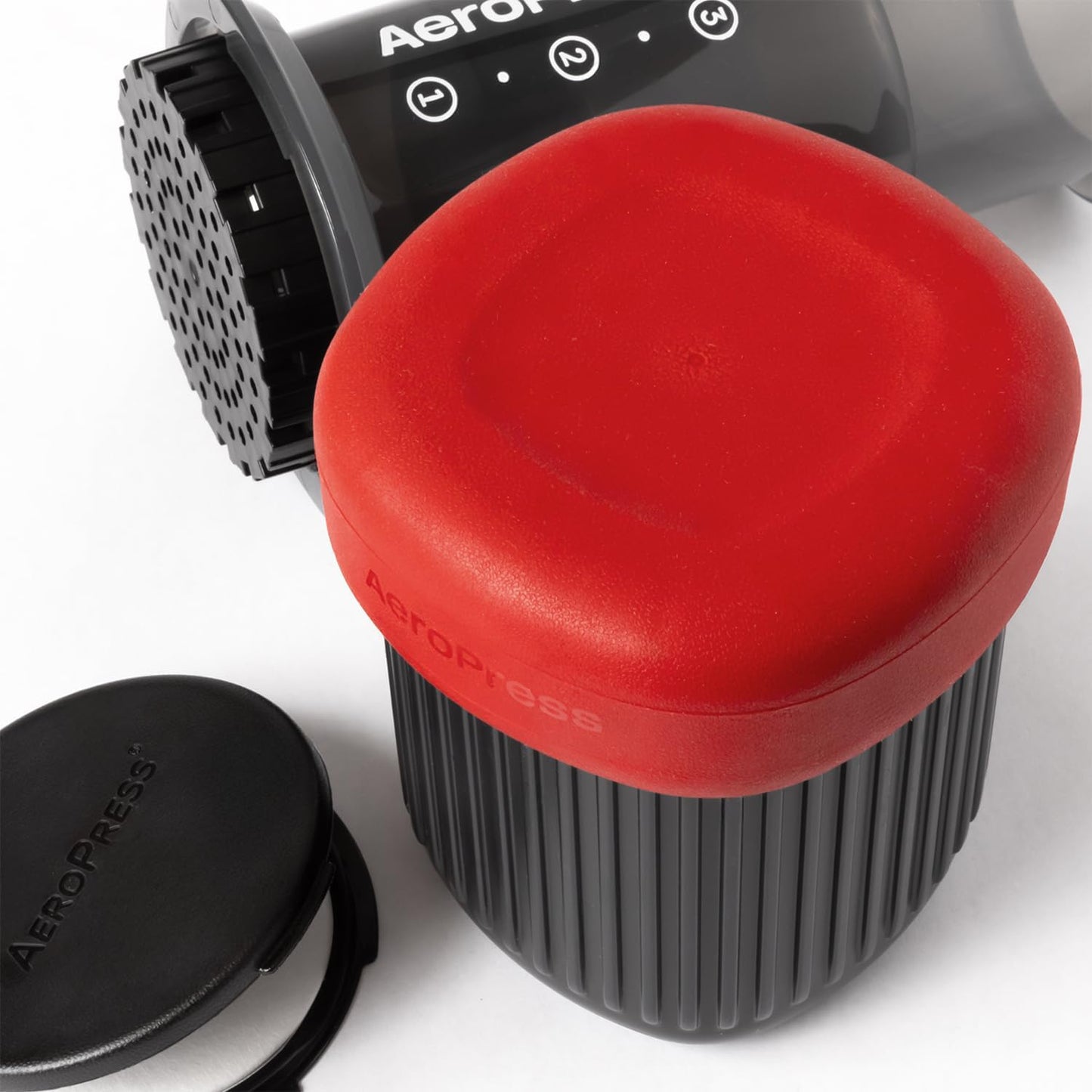 Aeropress coffee maker with red lid on a white background