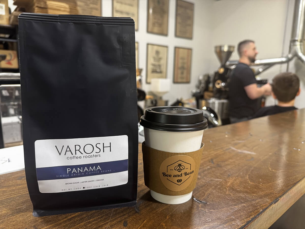 VAROSH coffee roasters bag and a coffee cup from Bee and Bean in Charlotte, while owner trains customers on specialty coffee roasting.