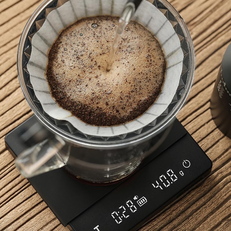 Coffee being brewed into a filter with a digital scale displaying weight on a wooden surface