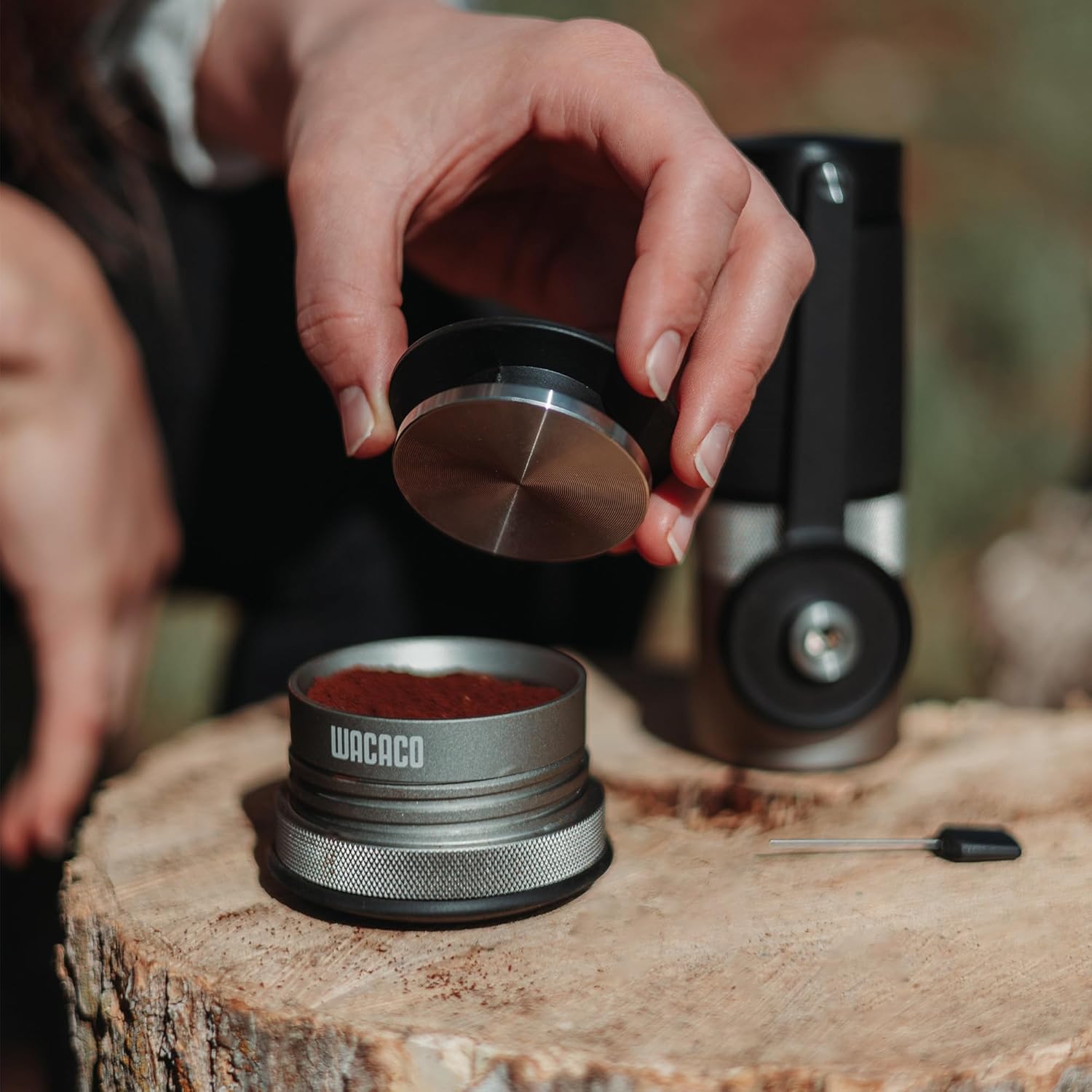 Person using a Wacaco coffee grinder on a wooden surface