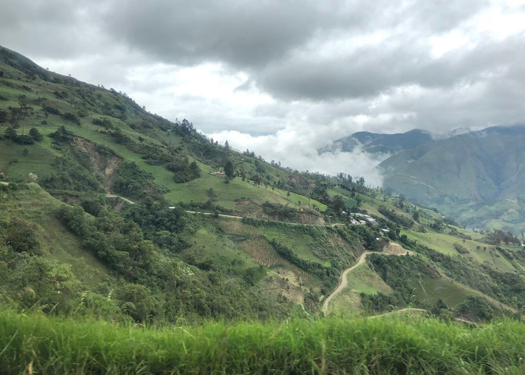 Green mountain landscape with winding road and cloudy sky